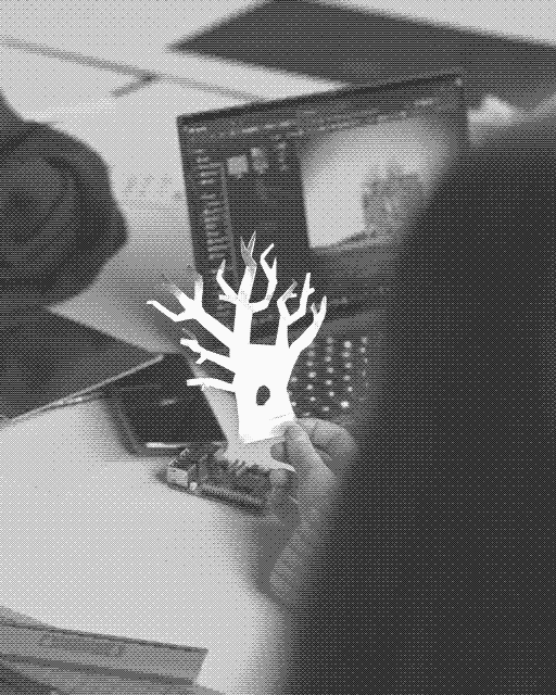 A paper tree held up in front of a laptop, a physical prototype meeting a model.